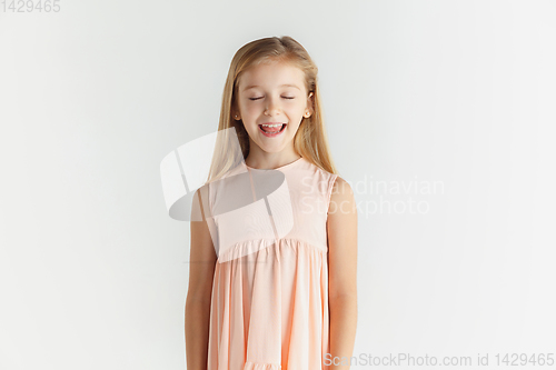 Image of Little smiling girl posing in dress on white studio background
