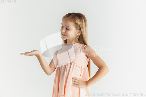 Image of Little smiling girl posing in dress on white studio background