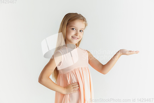 Image of Little smiling girl posing in dress on white studio background