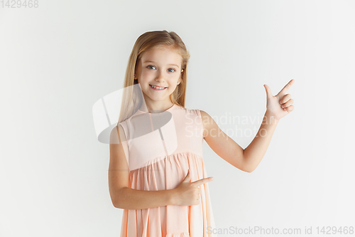 Image of Little smiling girl posing in dress on white studio background
