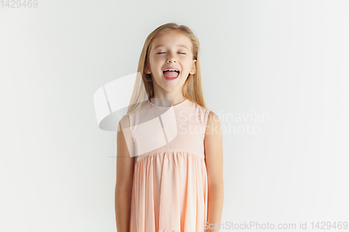 Image of Little smiling girl posing in dress on white studio background