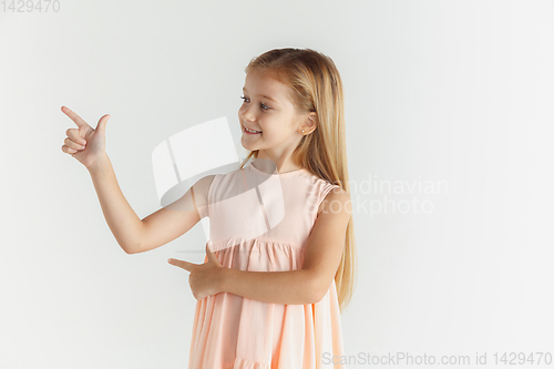Image of Little smiling girl posing in dress on white studio background