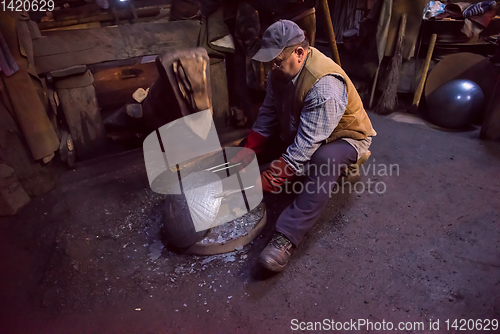 Image of blacksmith workers using mechanical hammer at workshop