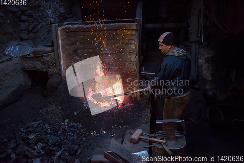 Image of young traditional Blacksmith working with open fire