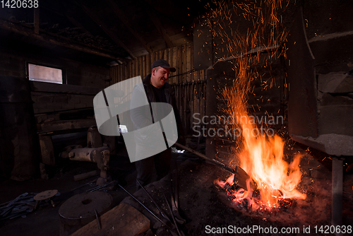 Image of young traditional Blacksmith working with open fire