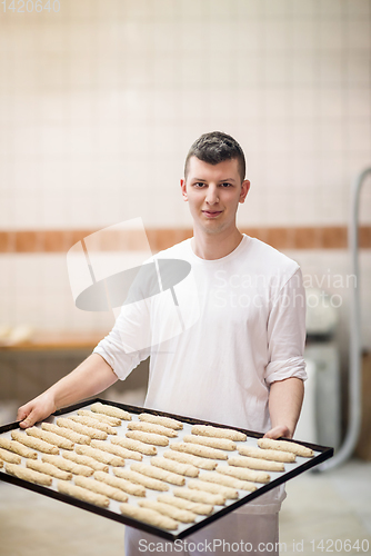 Image of A young baker holding raw product of white dough