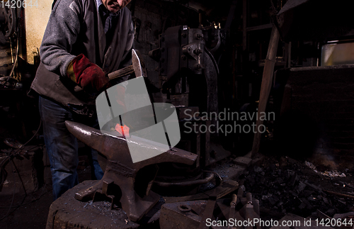 Image of blacksmith manually forging the molten metal