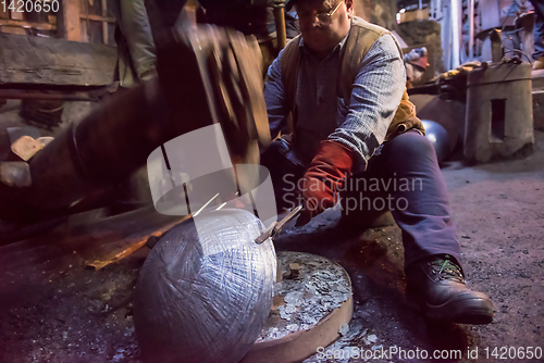 Image of blacksmith workers using mechanical hammer at workshop