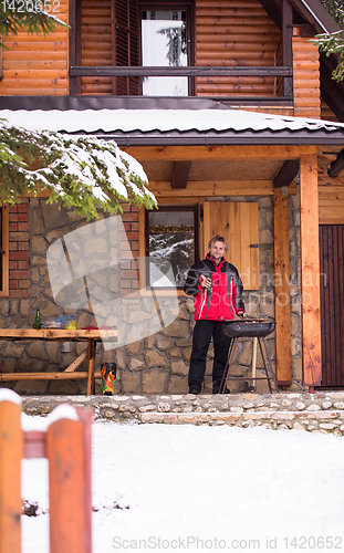 Image of young man cooking meat on barbecue