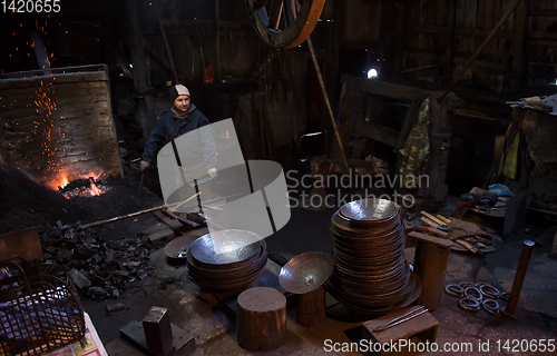 Image of young traditional Blacksmith working with open fire