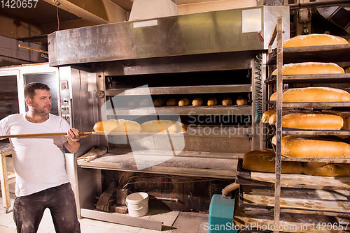 Image of bakery worker taking out freshly baked breads