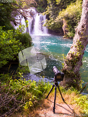 Image of profesional DSLR camera on a tripod at beautiful waterfall