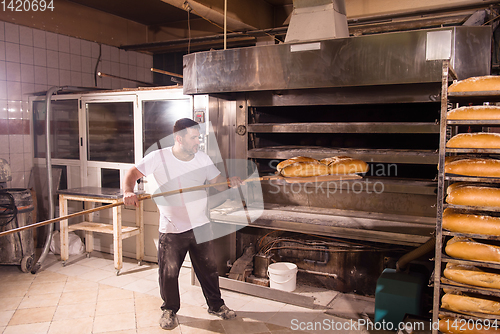 Image of bakery worker taking out freshly baked breads