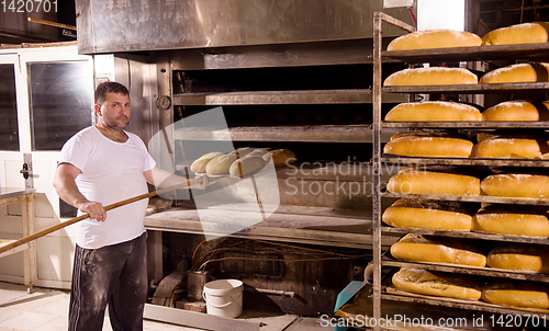 Image of bakery worker taking out freshly baked breads