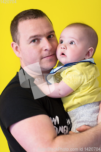 Image of portrait of happy young father holding baby isolated on yellow