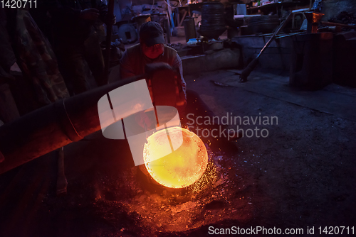 Image of blacksmith workers using mechanical hammer at workshop