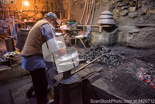 Image of traditional blacksmith manually forging the molten metal