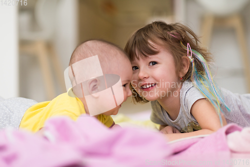 Image of little sister and her baby brother playing at home