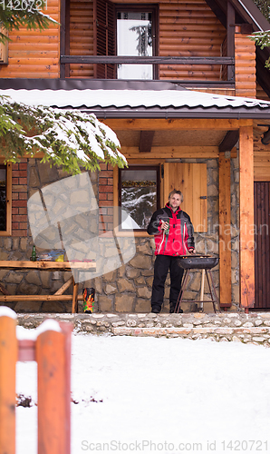 Image of young man cooking meat on barbecue