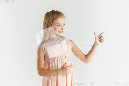 Image of Little smiling girl posing in dress on white studio background