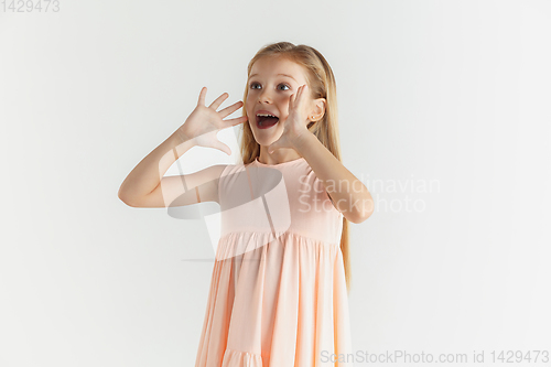 Image of Little smiling girl posing in dress on white studio background