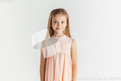 Image of Little smiling girl posing in dress on white studio background
