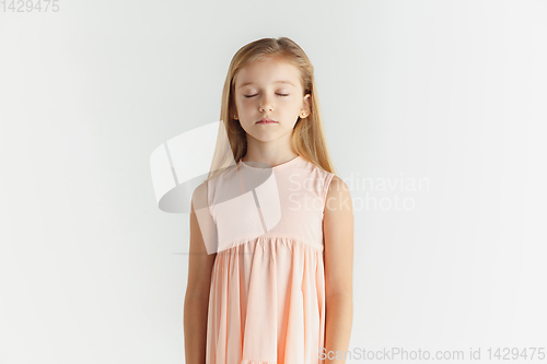 Image of Little smiling girl posing in dress on white studio background