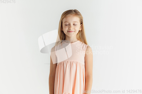 Image of Little smiling girl posing in dress on white studio background