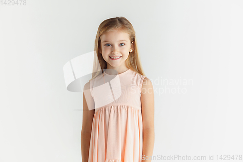 Image of Little smiling girl posing in dress on white studio background