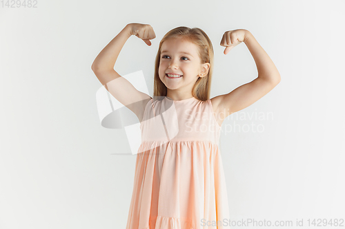 Image of Little smiling girl posing in dress on white studio background
