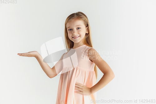 Image of Little smiling girl posing in dress on white studio background