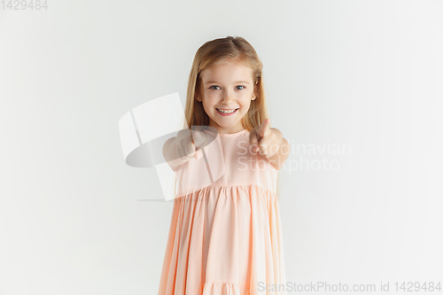 Image of Little smiling girl posing in dress on white studio background