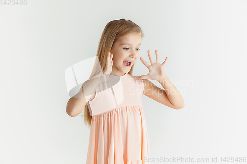 Image of Little smiling girl posing in dress on white studio background