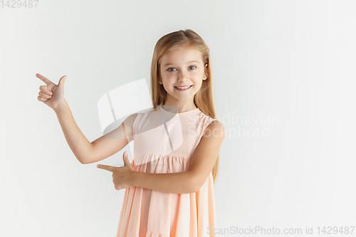 Image of Little smiling girl posing in dress on white studio background