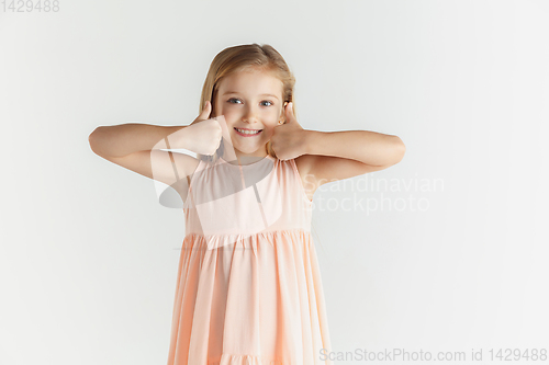 Image of Little smiling girl posing in dress on white studio background