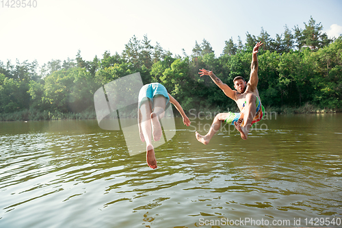 Image of Happy friends having fun, ready to jump and swim in river