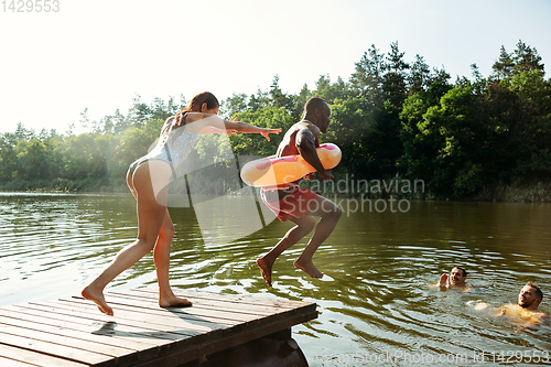 Image of Happy friends having fun, jumping and swimming in river