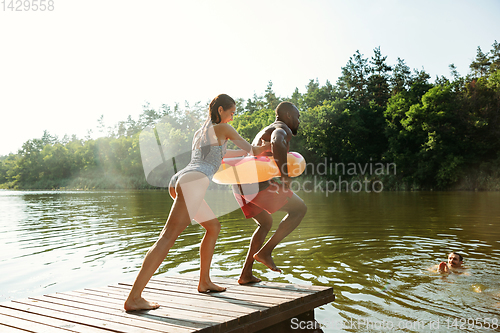 Image of Happy friends having fun, jumping and swimming in river