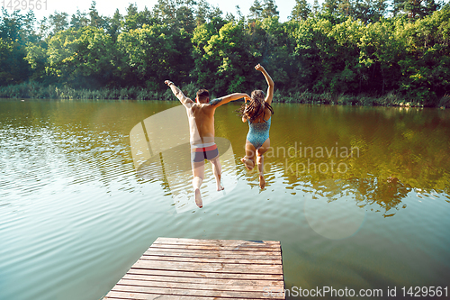 Image of Happy friends having fun, jumping and swimming in river