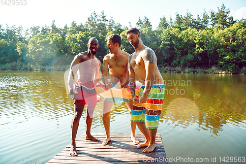 Image of Happy friends having fun, ready to jump and swim in river