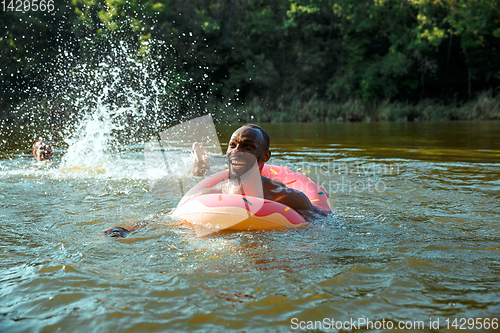 Image of Happy man having fun, laughting and swimming in river