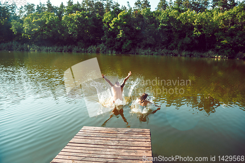 Image of Happy friends having fun, jumping and swimming in river