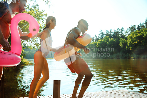 Image of Happy friends having fun, jumping and swimming in river