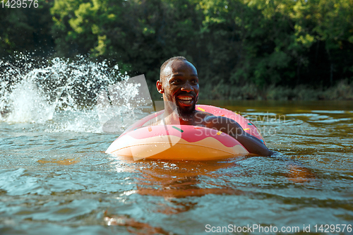 Image of Happy man having fun, laughting and swimming in river