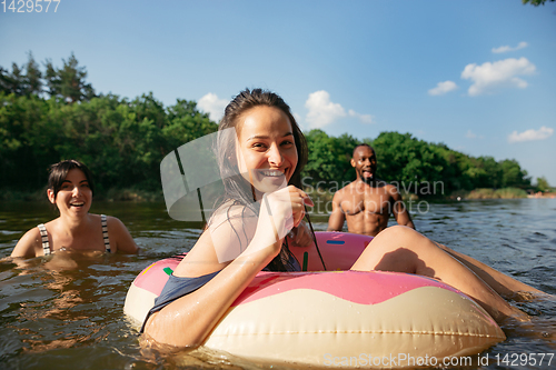 Image of Happy group of friends having fun, laughting and swimming in river