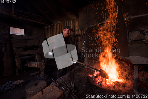 Image of young traditional Blacksmith working with open fire