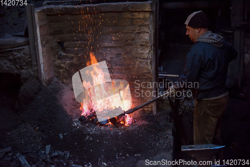 Image of young traditional Blacksmith working with open fire
