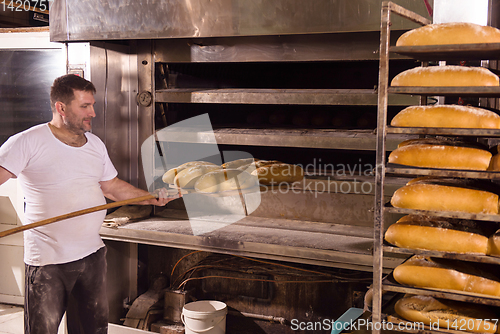 Image of bakery worker taking out freshly baked breads