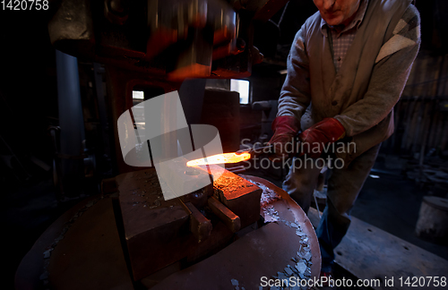 Image of blacksmith manually forging the molten metal