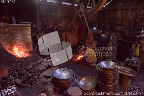 Image of blacksmith workers using mechanical hammer at workshop